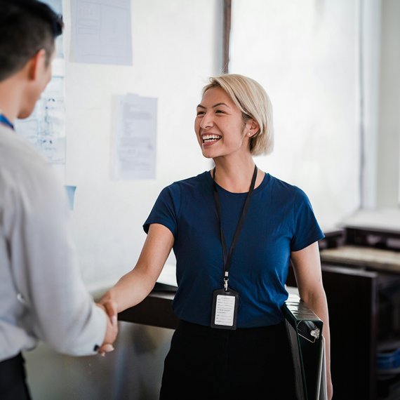 Two individuals in professional setting engaging in handshake