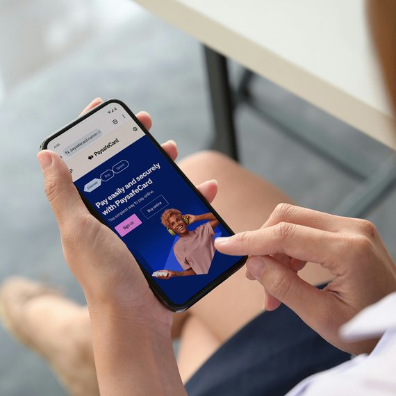 Person holding smartphone with PaysafeCard app on screen