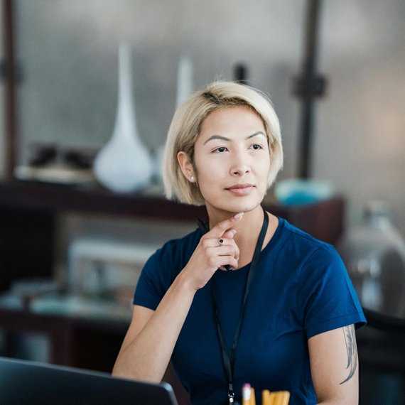 Woman with tattoo working on laptop in blue shirt