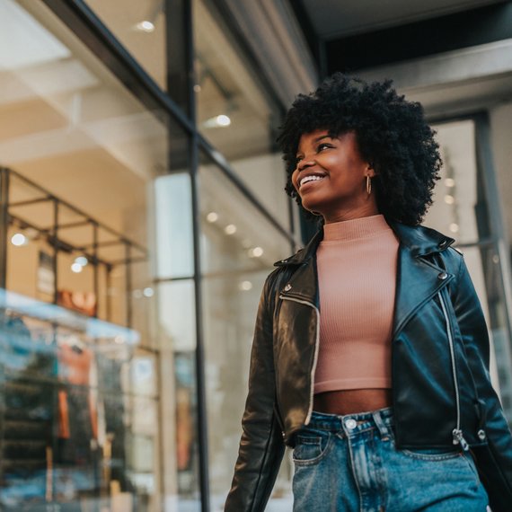 Person in leather jacket walking by storefront