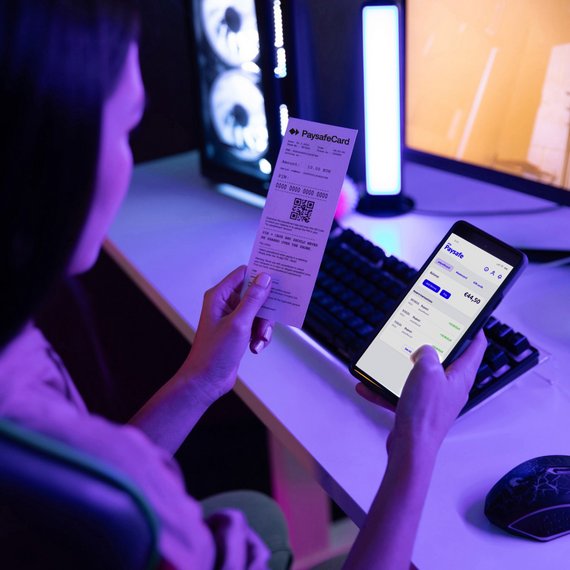 Person comparing receipt with smartphone app in dimly lit room