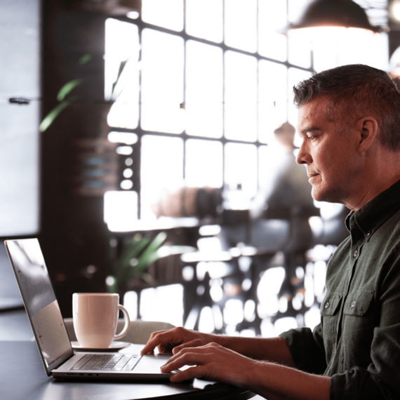 Individual in front of laptop, cup on desk